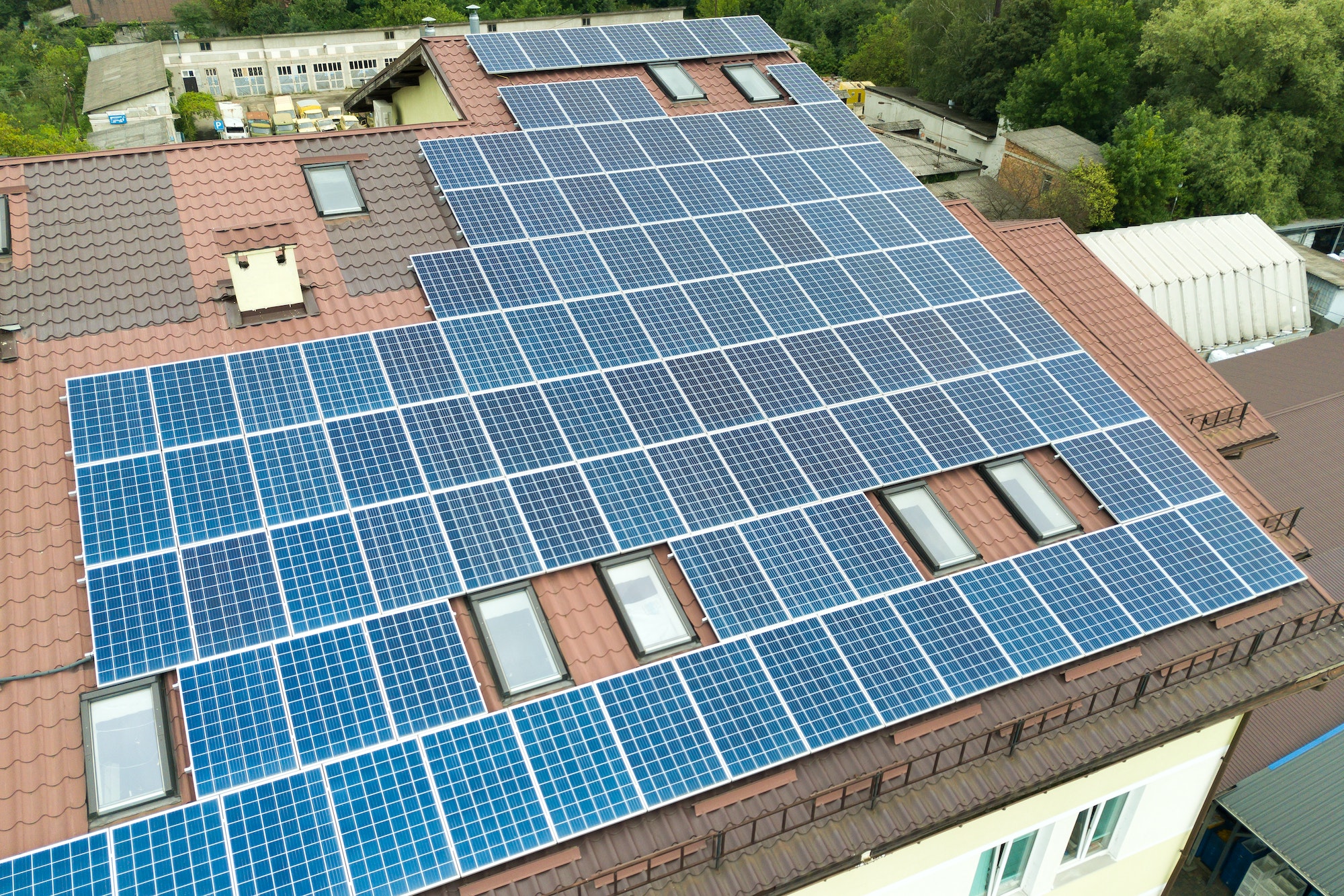 Aerial view of solar power plant with blue photovoltaic panels mounted of apartment building roof